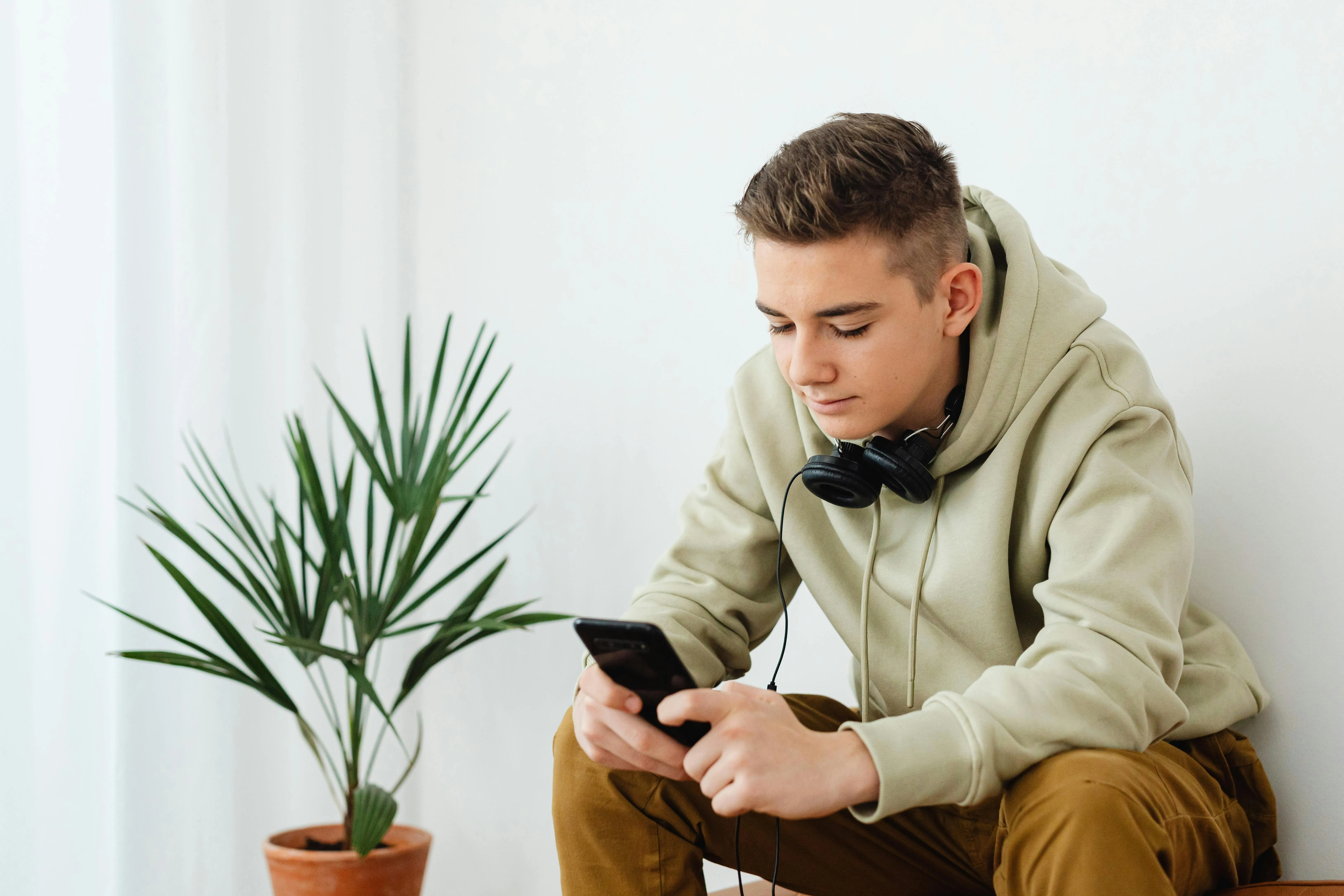 Парень читает сообщения в смартфоне дома
