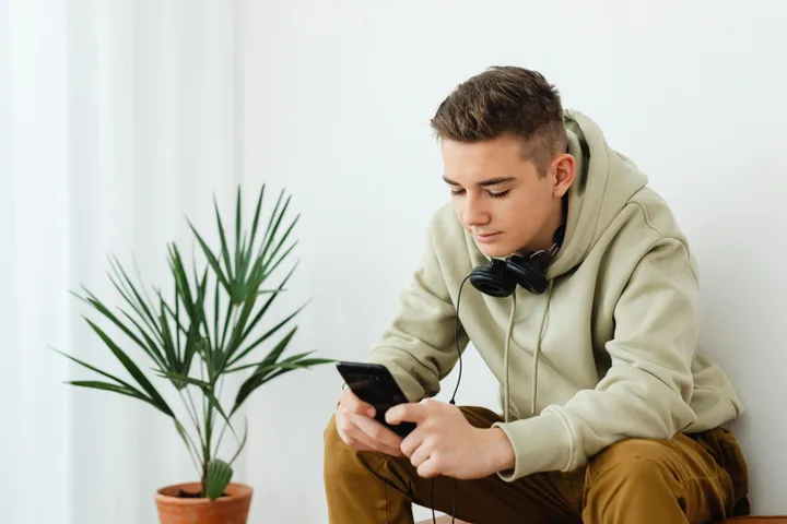 Парень читает сообщения в смартфоне дома