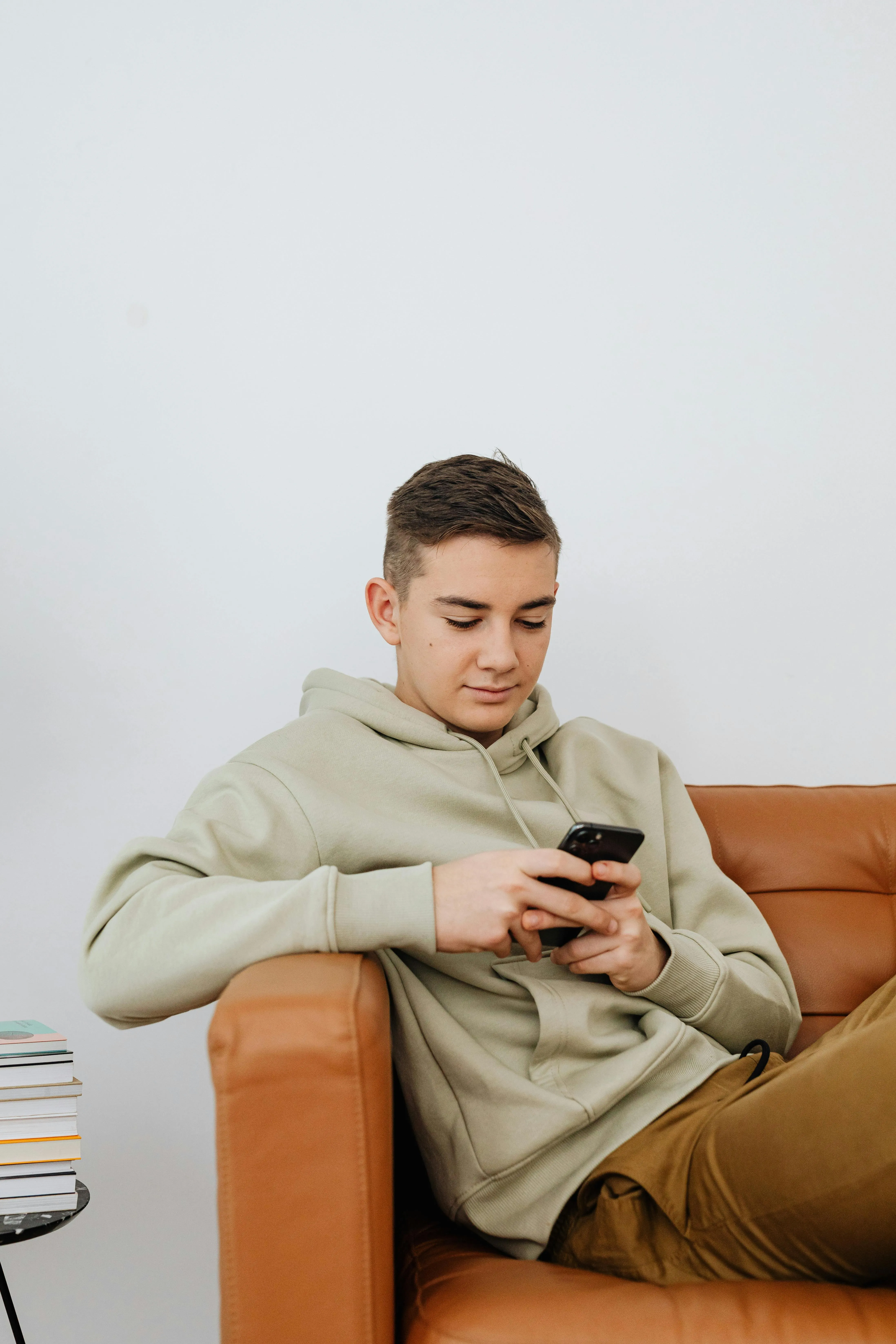 Парень сидит на диване и переписывается в смартфоне